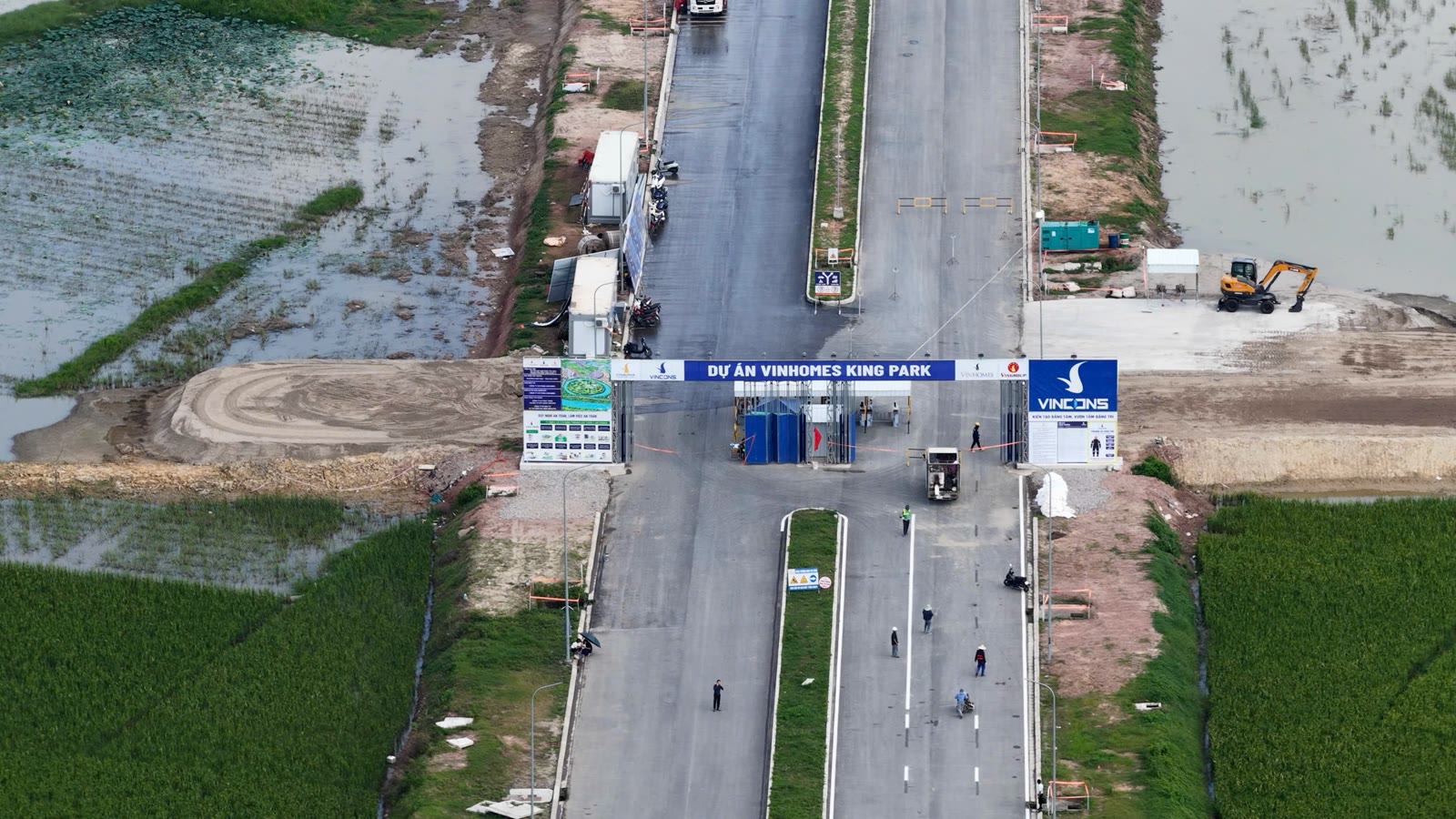 Ảnh chụp từ trên cao cổng dự án Vinhomes King Park và trục đường chính đang thi công giữa cánh đồng
