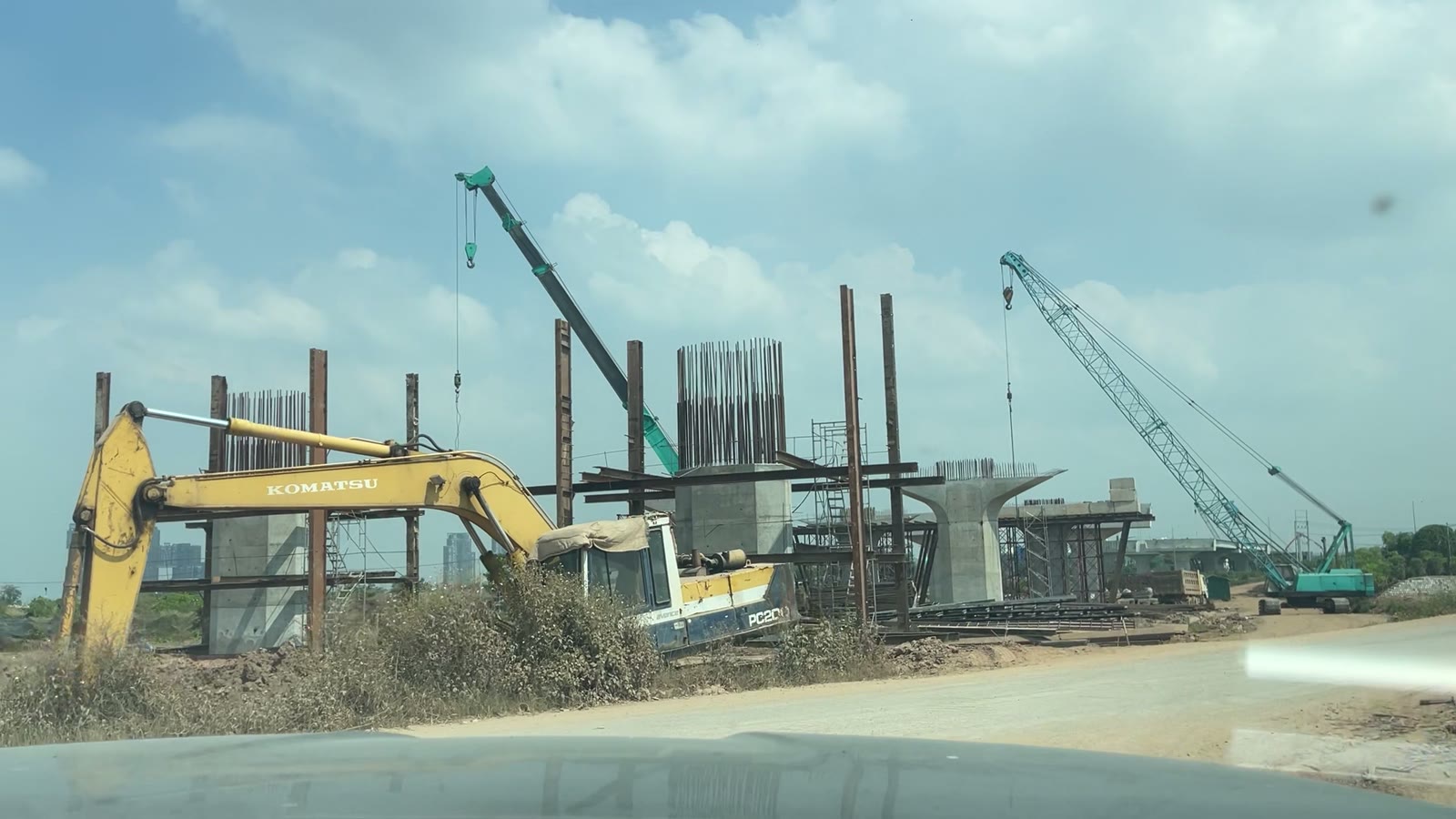 Máy xúc và cần cẩu bên hàng trụ cầu dẫn cầu Ngọc Hồi đang thi công trên bãi sông gần Bát Tràng
